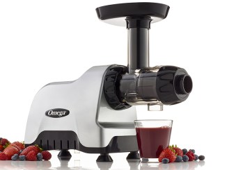 Juicer with glass of juice, strawberries and blueberries