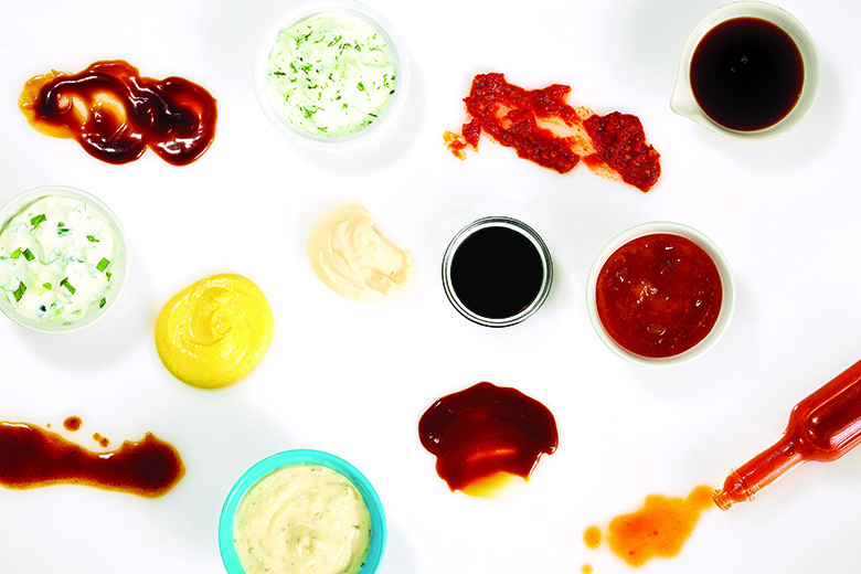 Different condiments on white background