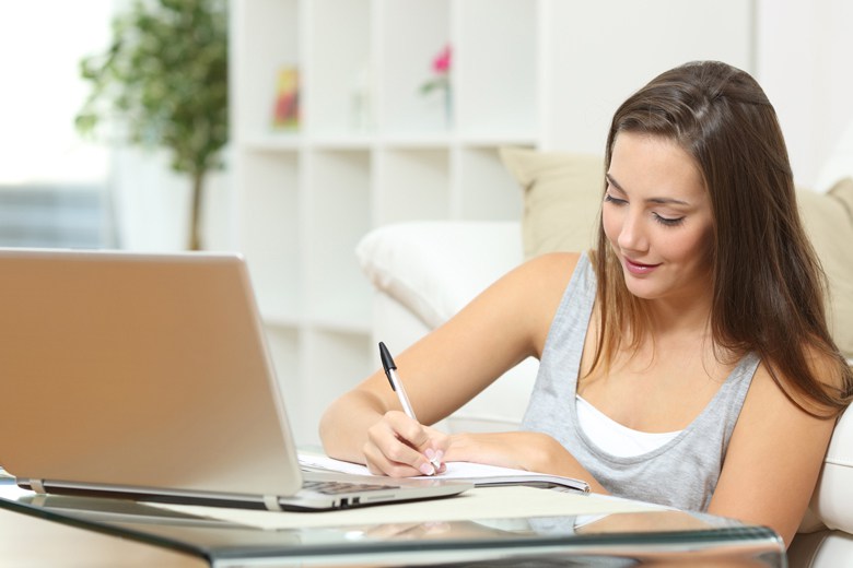 Student studying at home and writing notes sitting on the floor