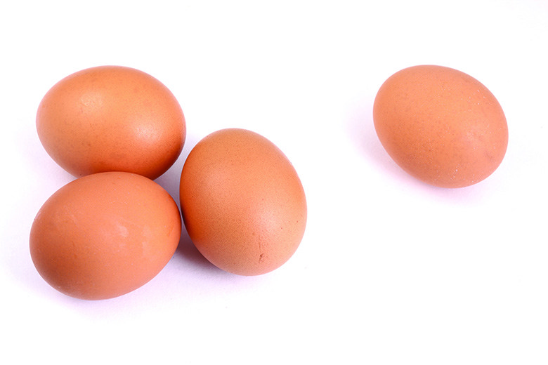 Four eggs in shell on white background