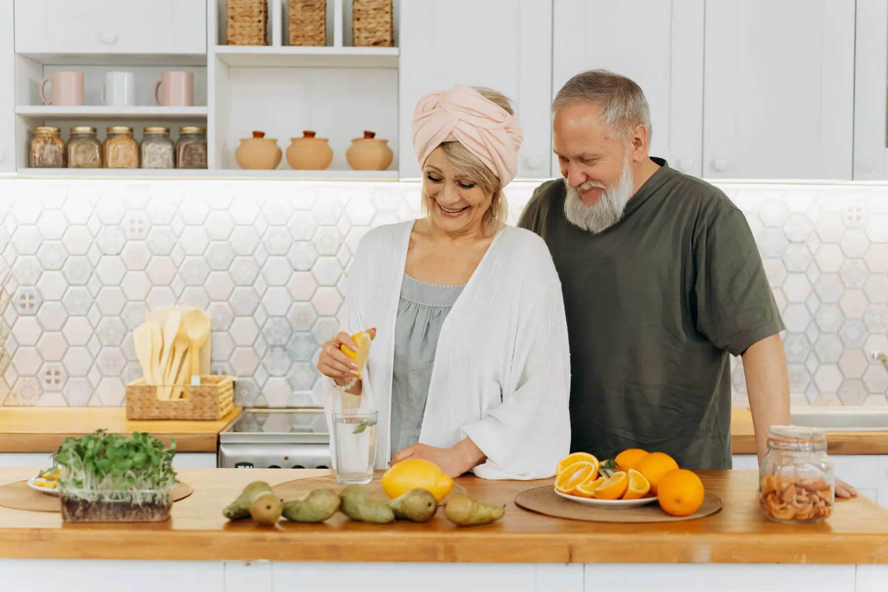 A senior couple squeezing citrus in a bright kitchen.