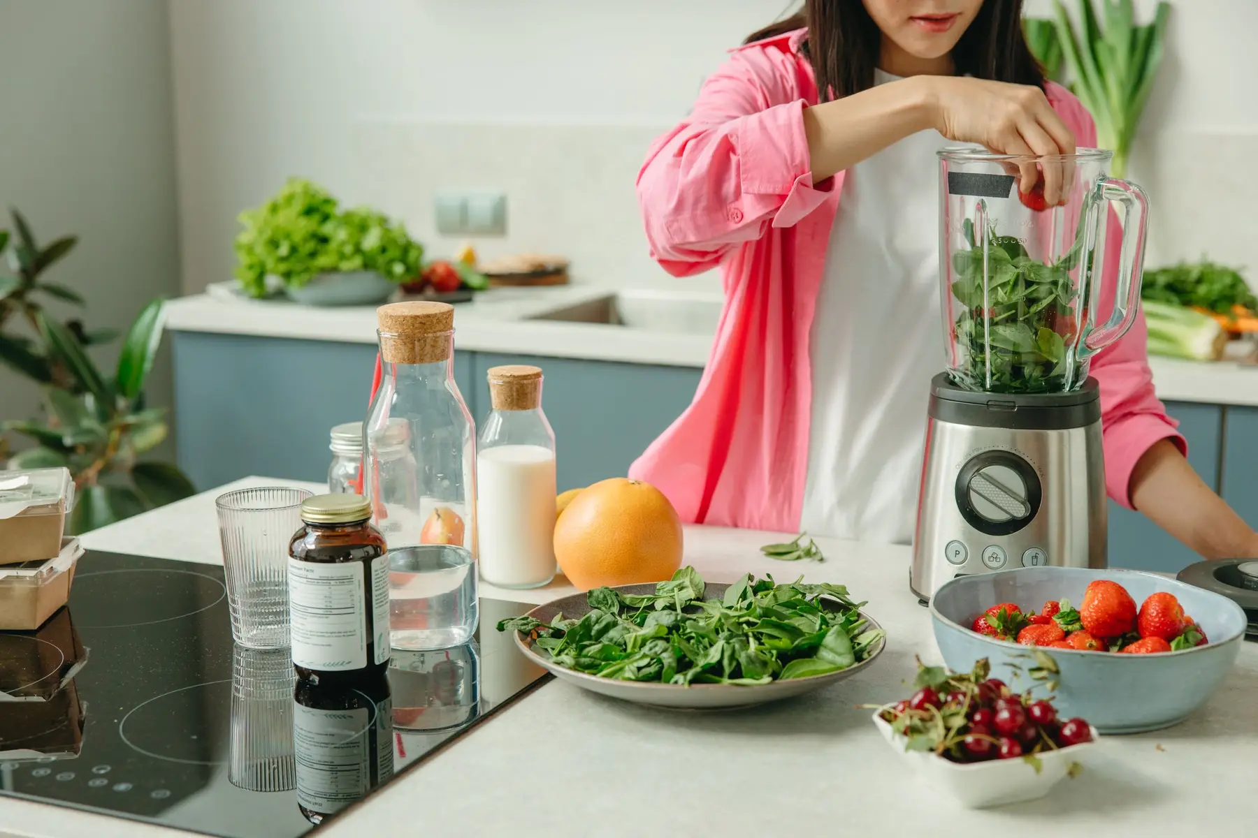 A woman blending a green drink in a bright kitchen