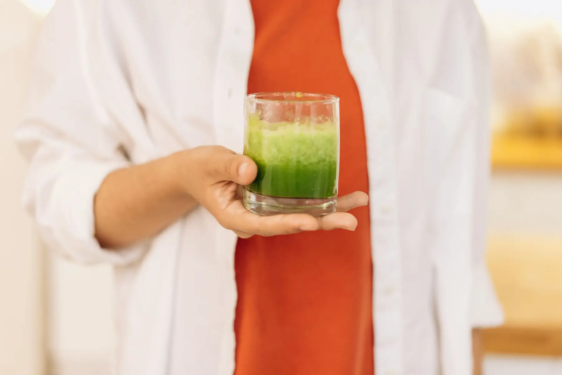 A person holding a glass of green smoothie.