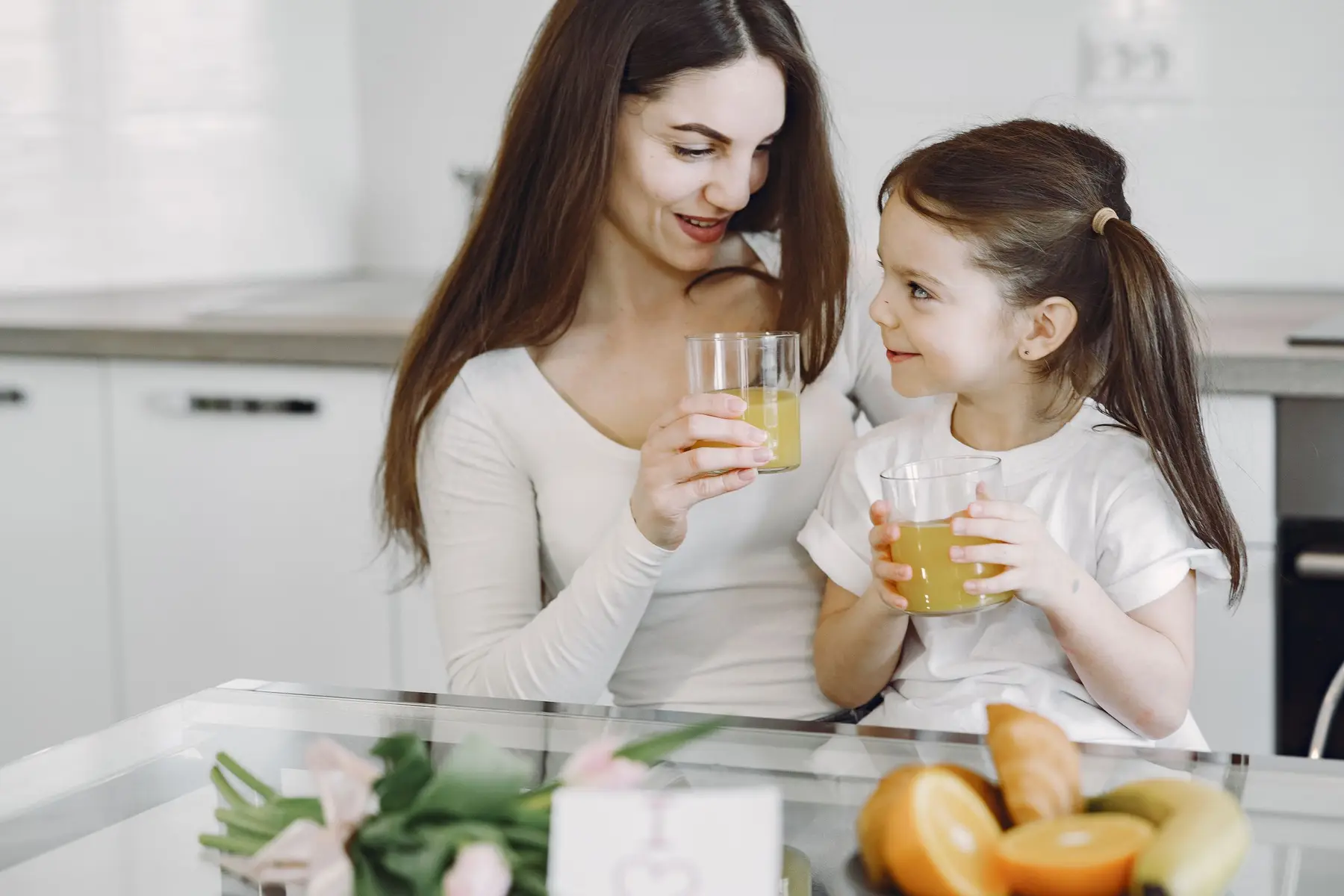 A mother and daughter sharing juice at breakfast.
