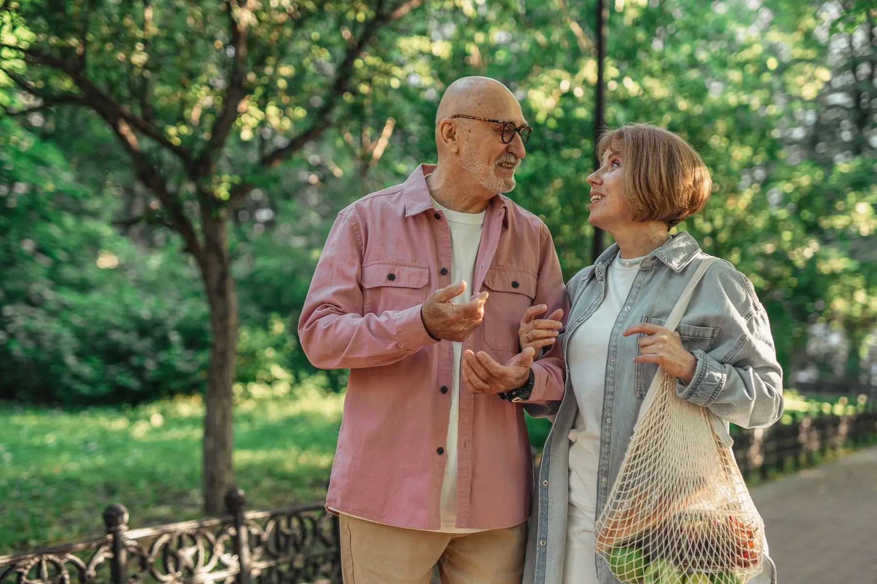 Senior couple walking together in a park enjoying a conversation on a sunny day