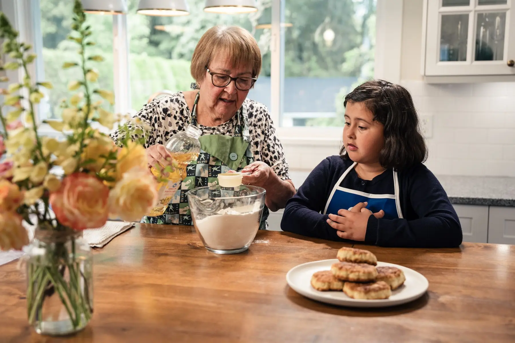 An intimate kitchen scene of a grandmother teaching her granddaughter how to bake traditional