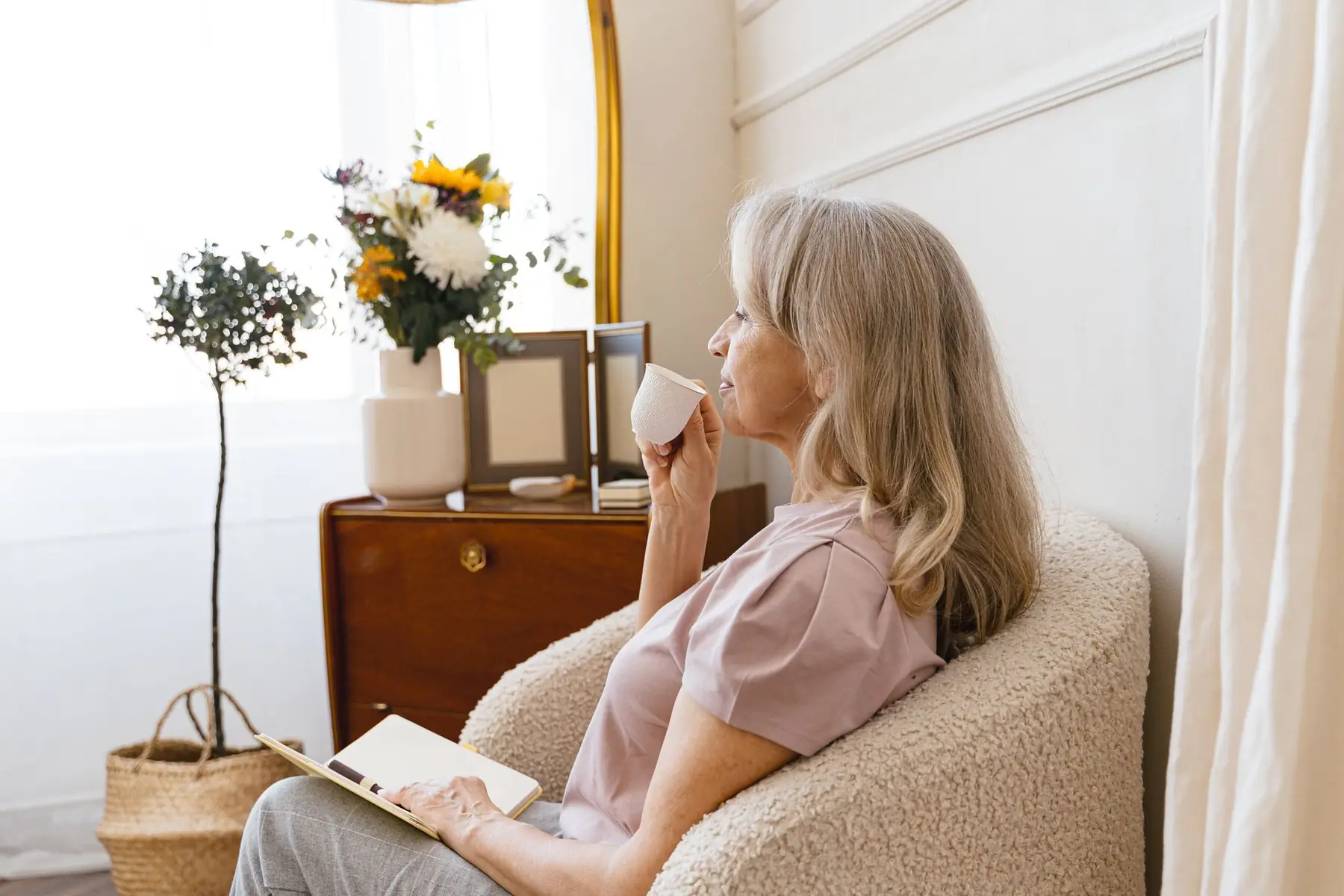 Senior woman relaxes with a cup of tea in a cozy indoor setting, side
