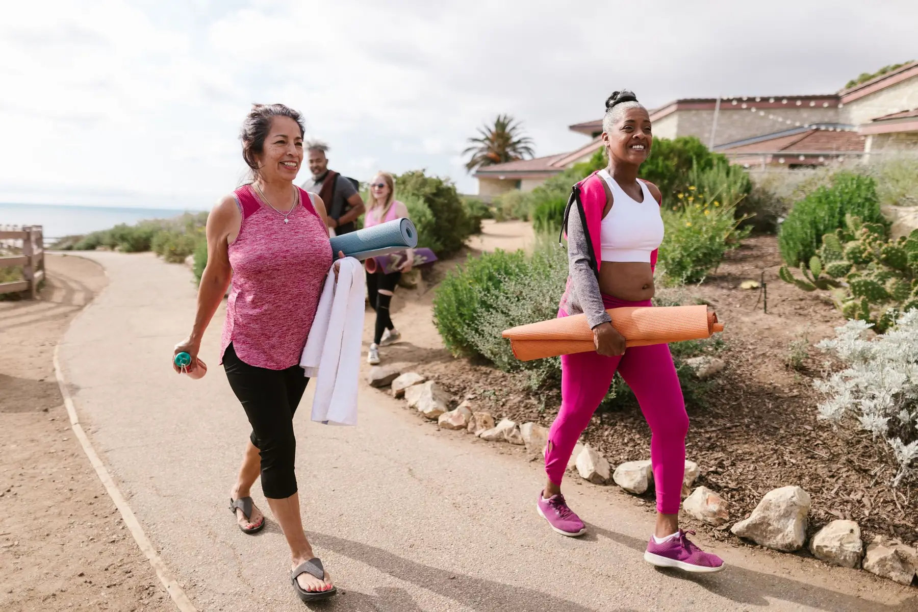 Women walking outdoors with yoga mats, enjoying a morning fitness session