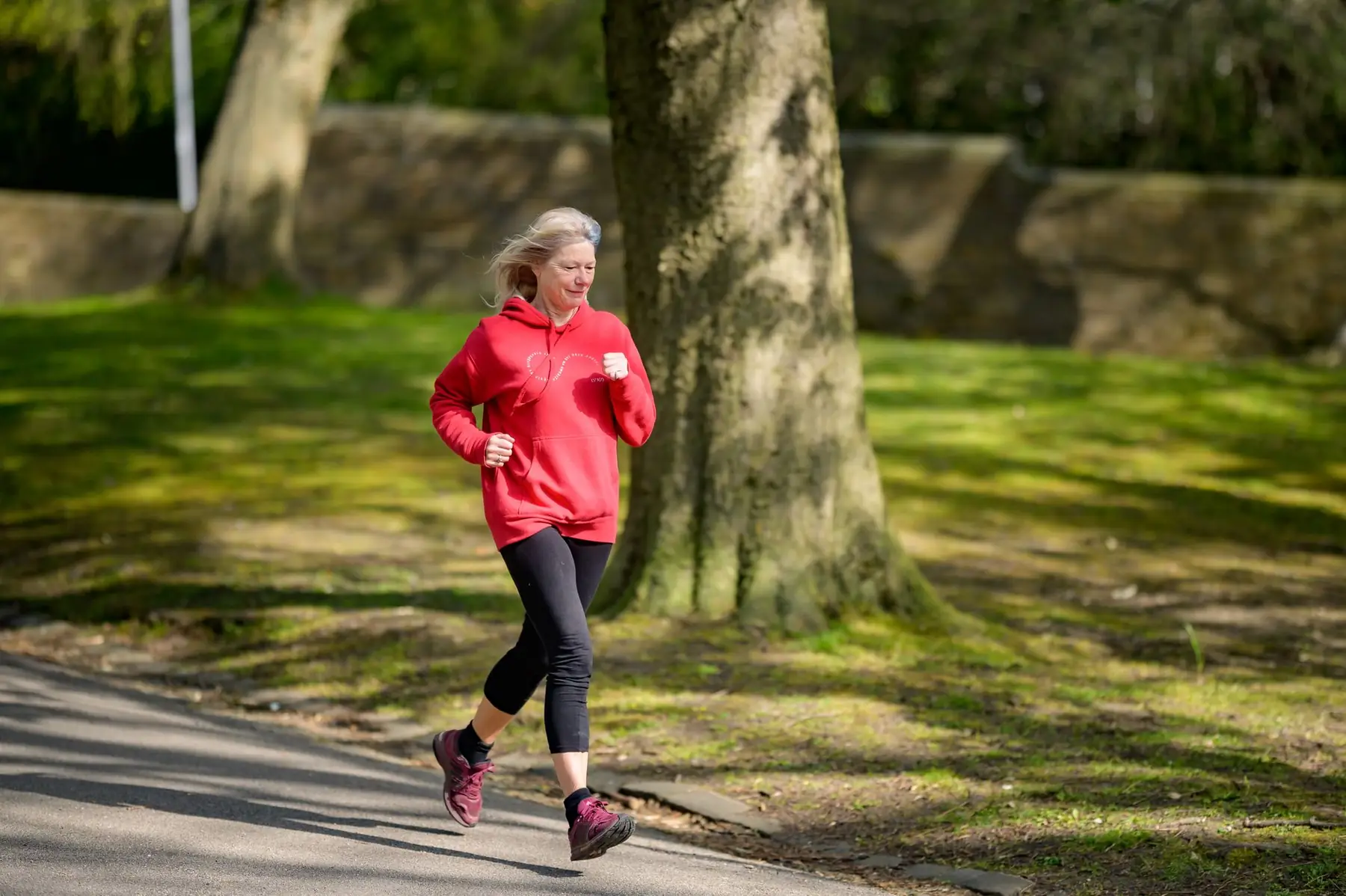 Elderly woman enjoying a healthy outdoor jog in a sunlit park