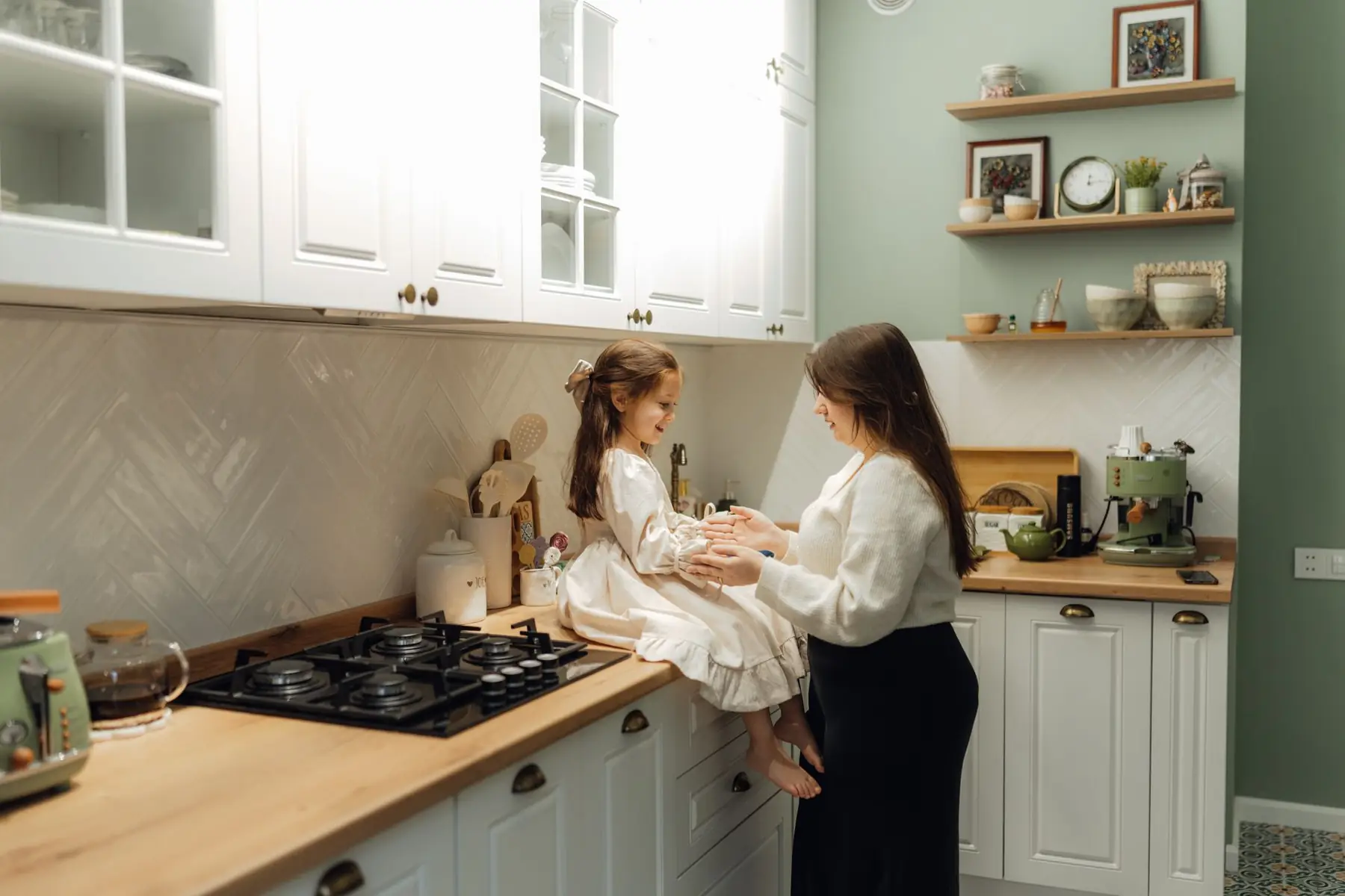A mother and her daughter share a tender moment in a cozy, well-decorated kitchen