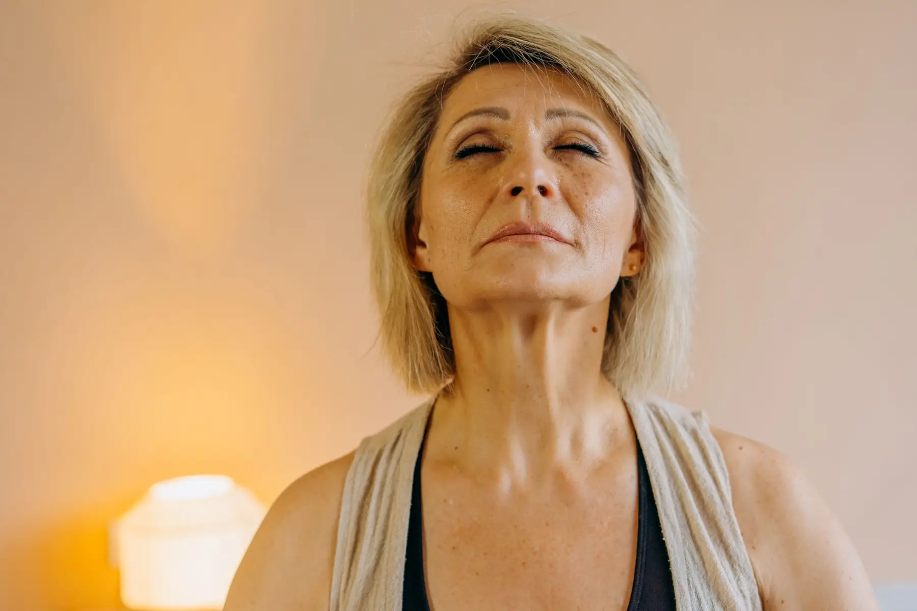 Serene elderly woman practicing mindfulness at home, eyes closed in peaceful relaxation