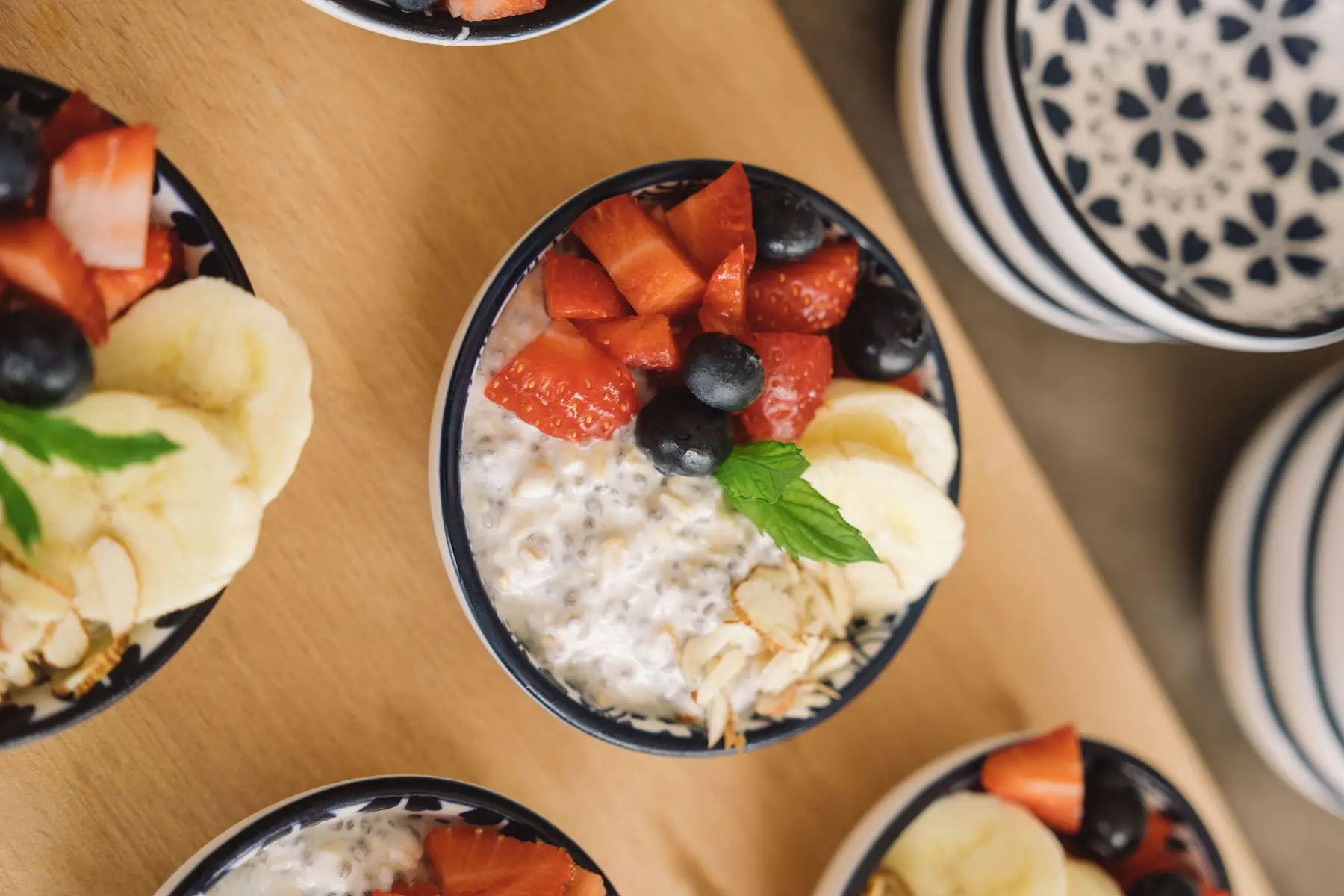 Bowls of oats topped with fresh fruit on a warm wooden table