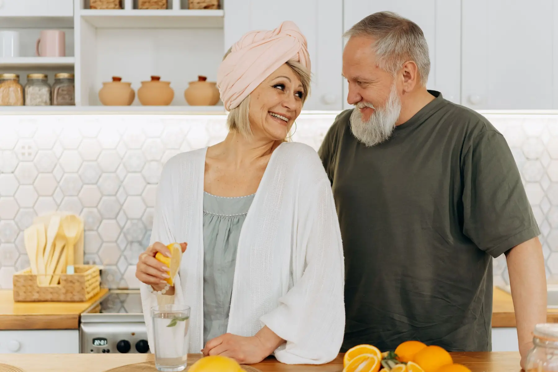A smiling older couple prepare fresh fruit together in a bright kitchen