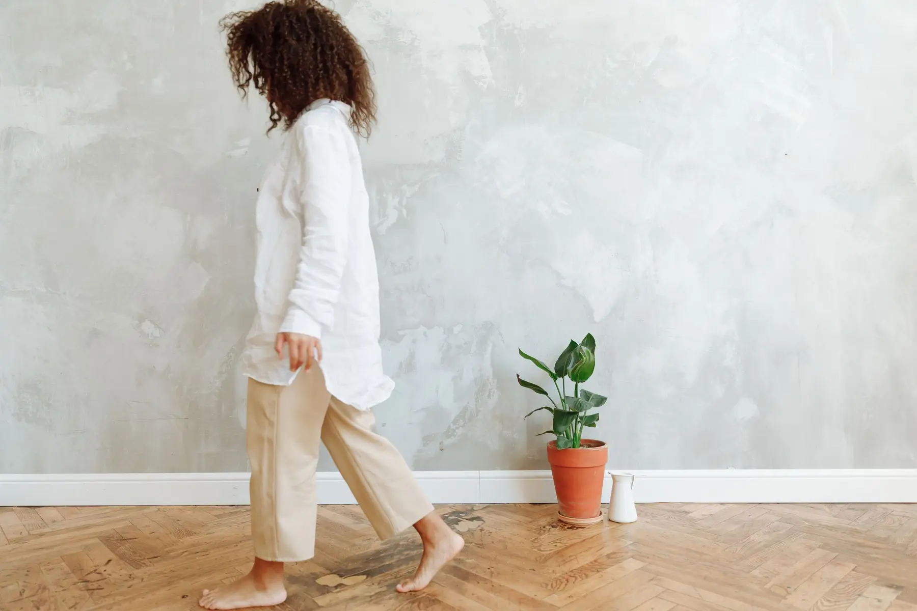 A woman walks barefoot across a bright living room floor at home