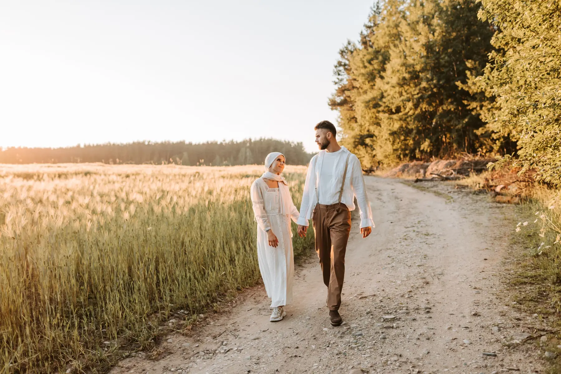 A couple walks hand in hand on a golden country path