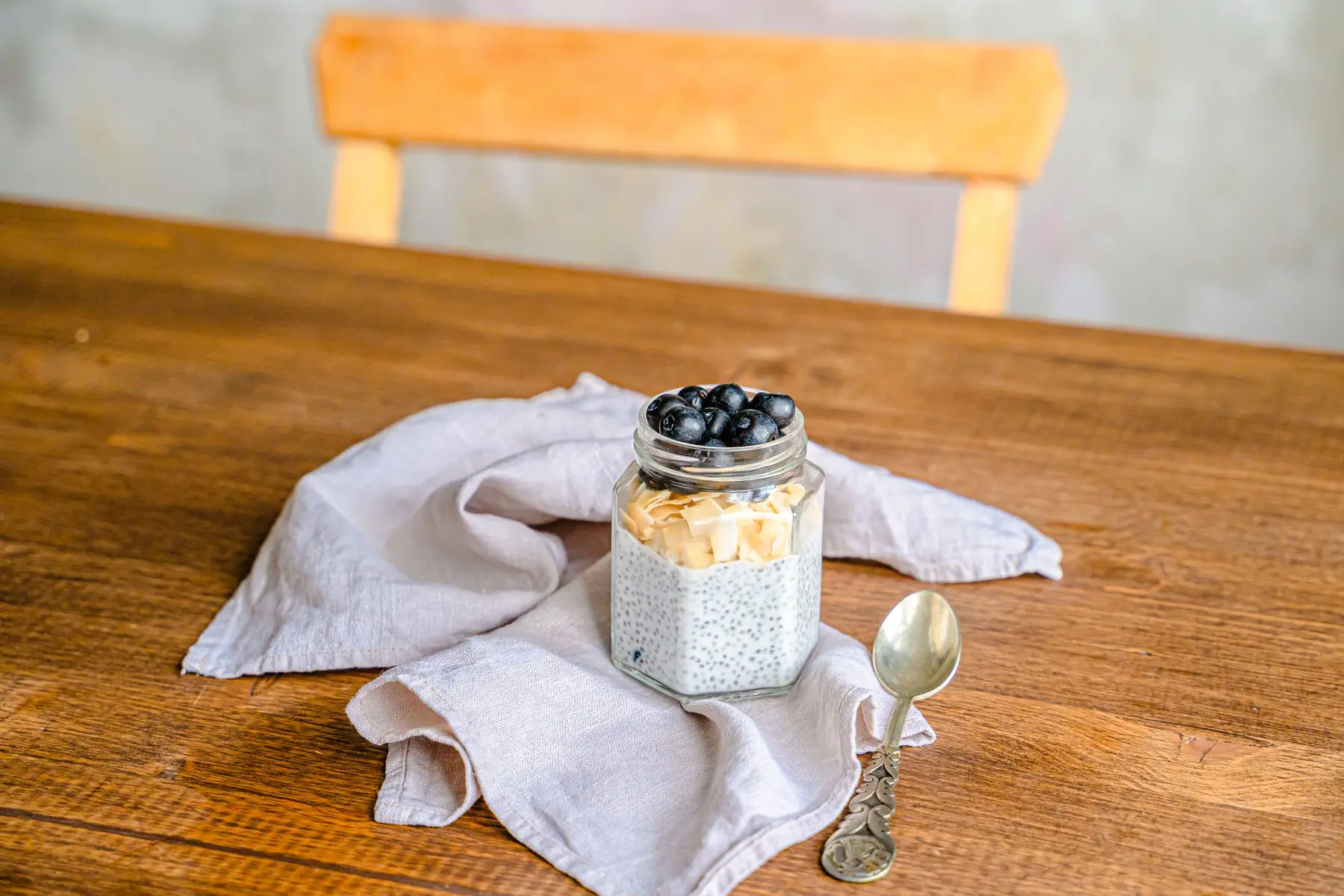 A jar of chia pudding with blueberries on a wooden table