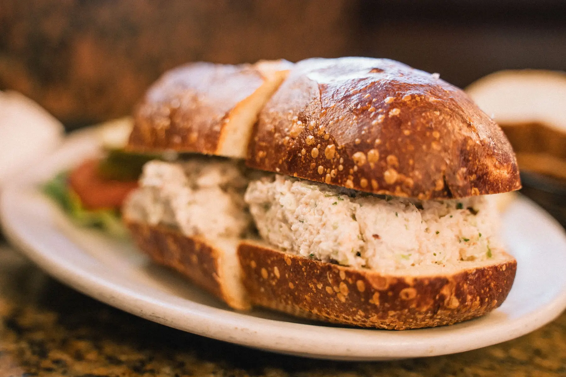 A chicken salad sandwich on rustic bread on a warm plate