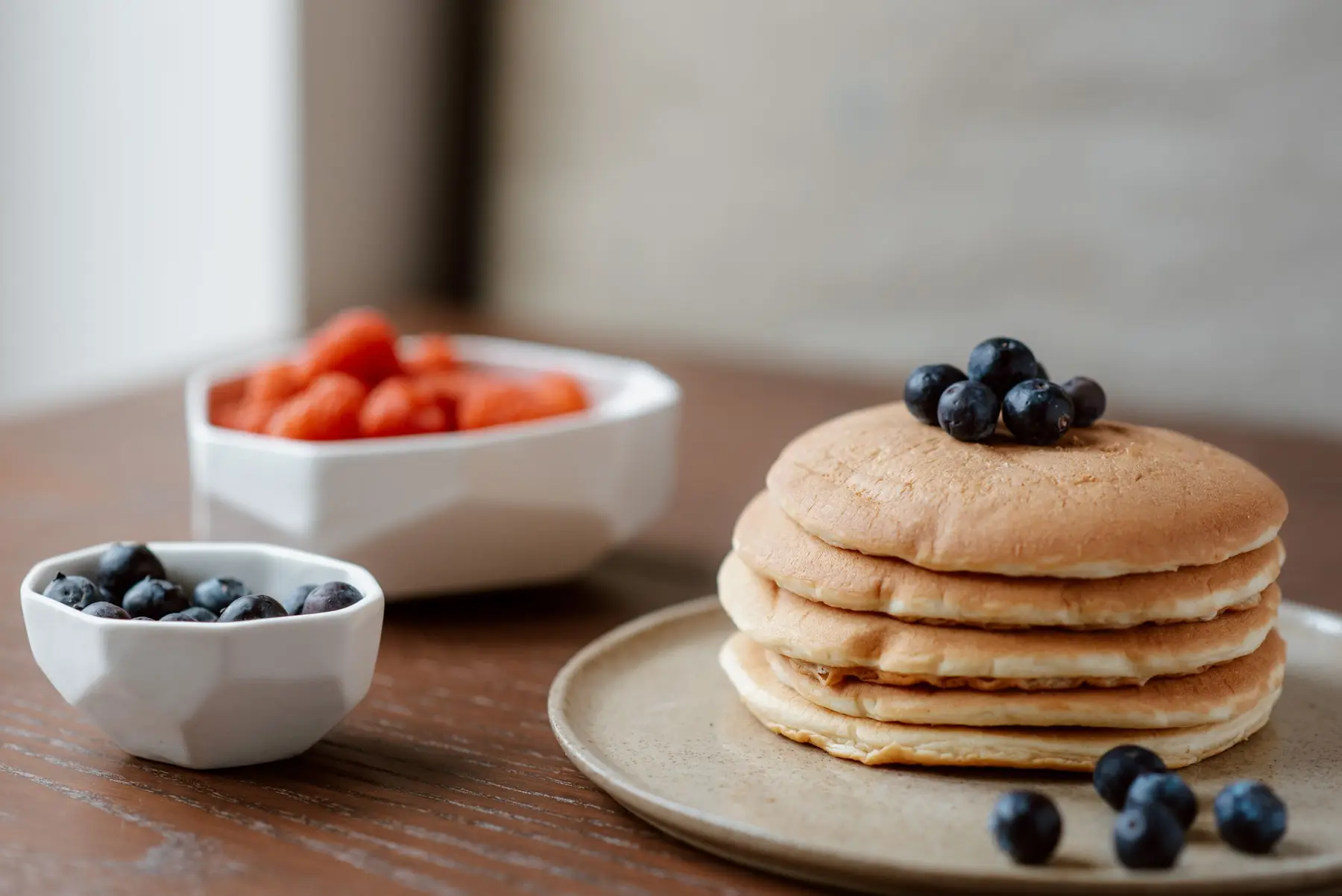 A stack of fluffy pancakes with blueberries on a wooden table