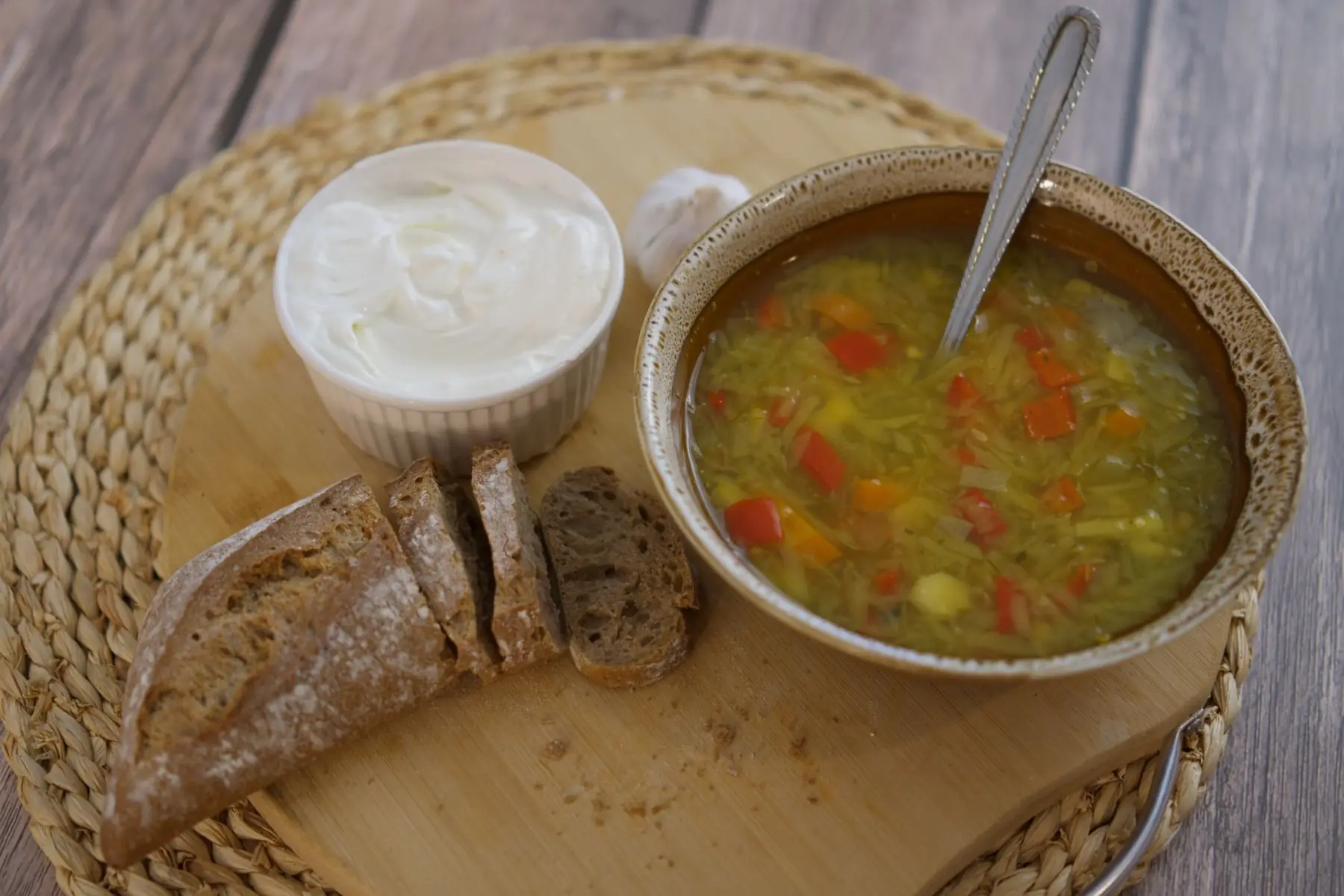 A cozy rustic lunch featuring vegetable soup with crusty bread and creamy spread