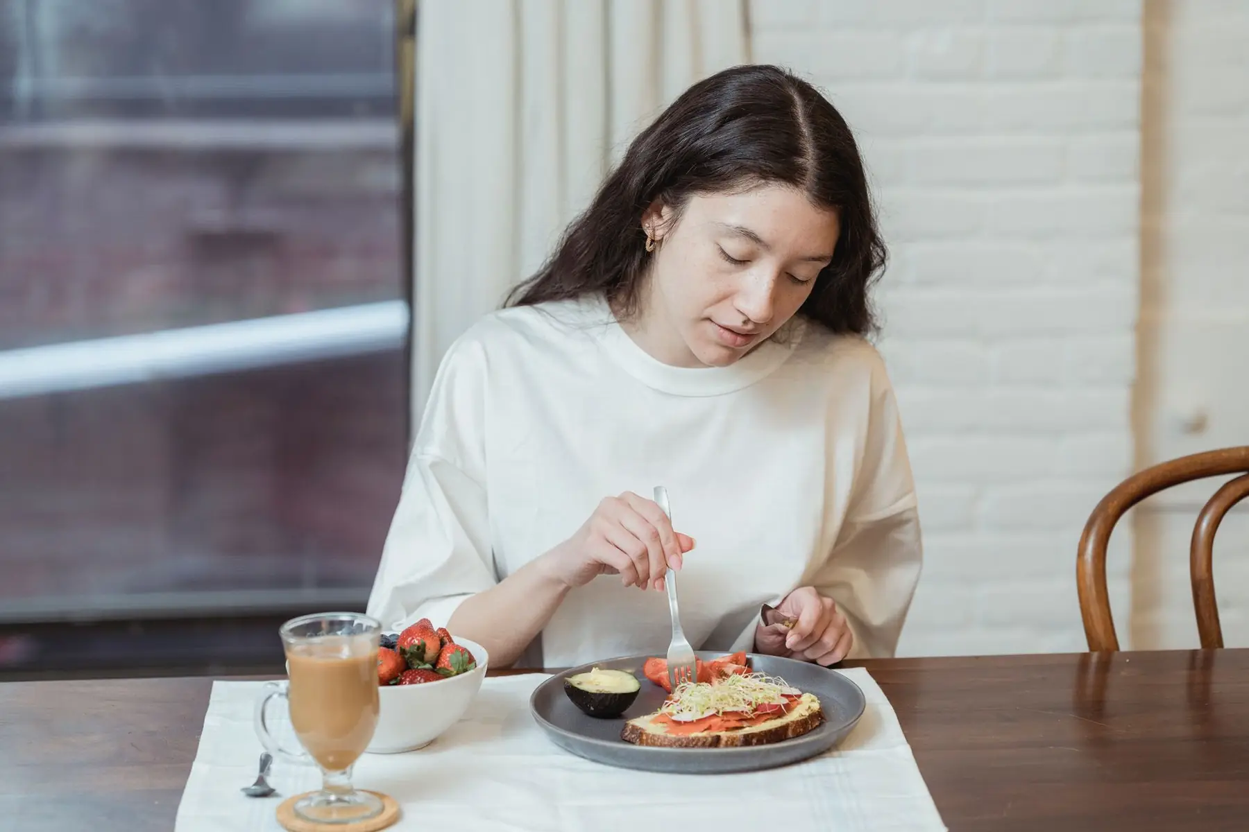 Woman having a nutritious breakfast with toast and strawberries in a cozy indoor setting