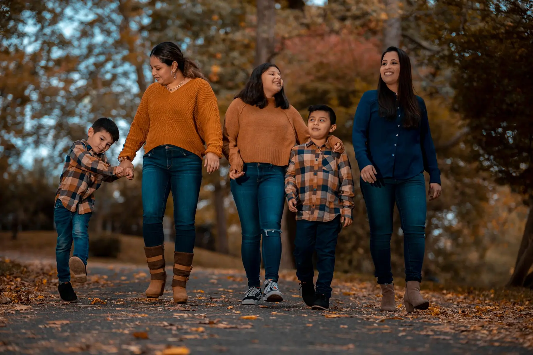 A family strolls through a park, enjoying the vibrant fall foliage