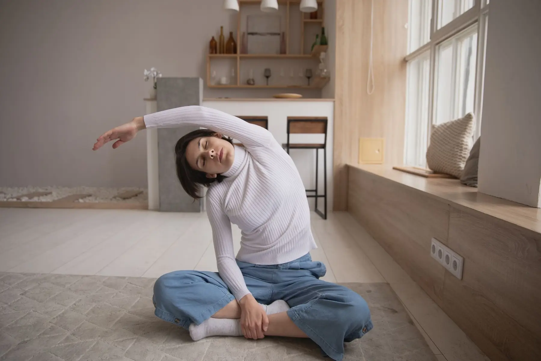 Woman performing a side stretch yoga pose indoors, emphasizing relaxation and fitness in a