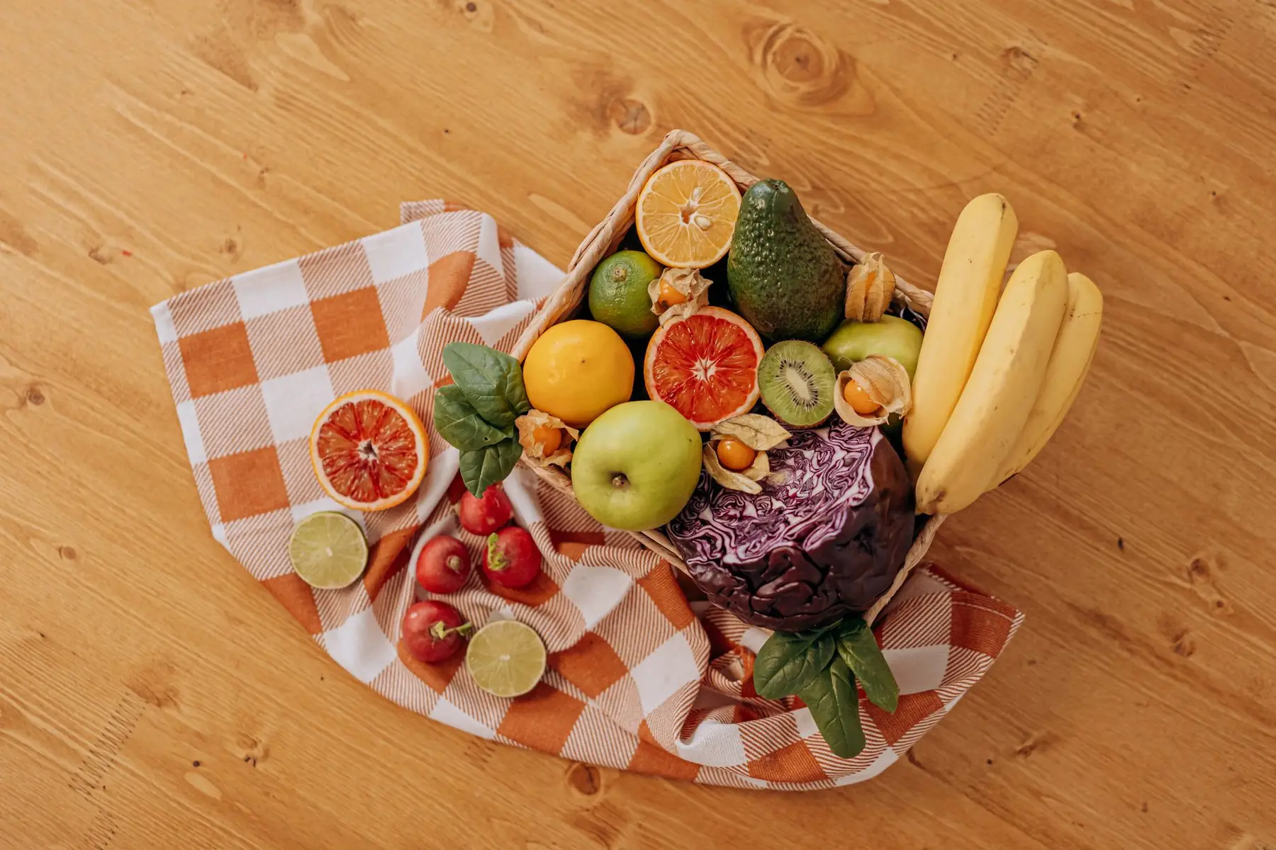 A vibrant flat lay of assorted fresh fruits on a checkered cloth over a