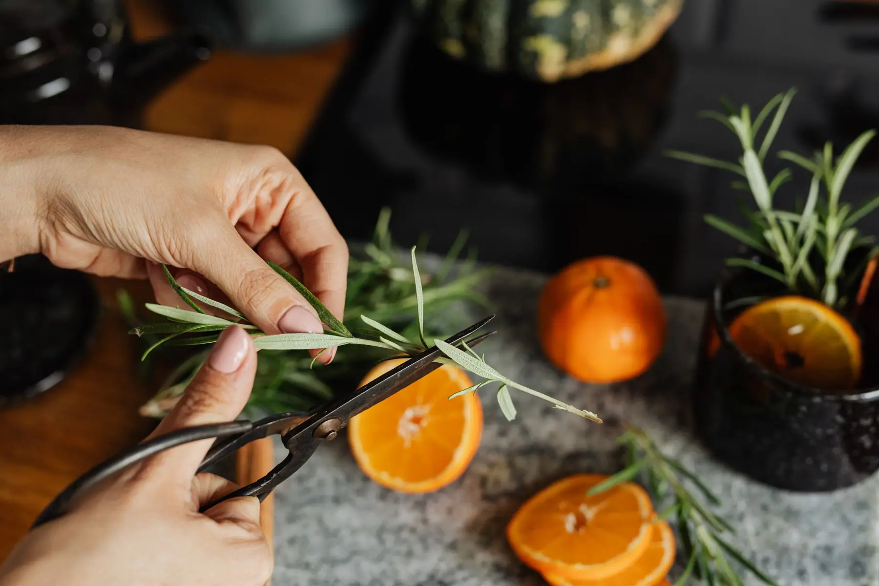Hands preparing fresh ingredients with oranges and herbs on a kitchen counter