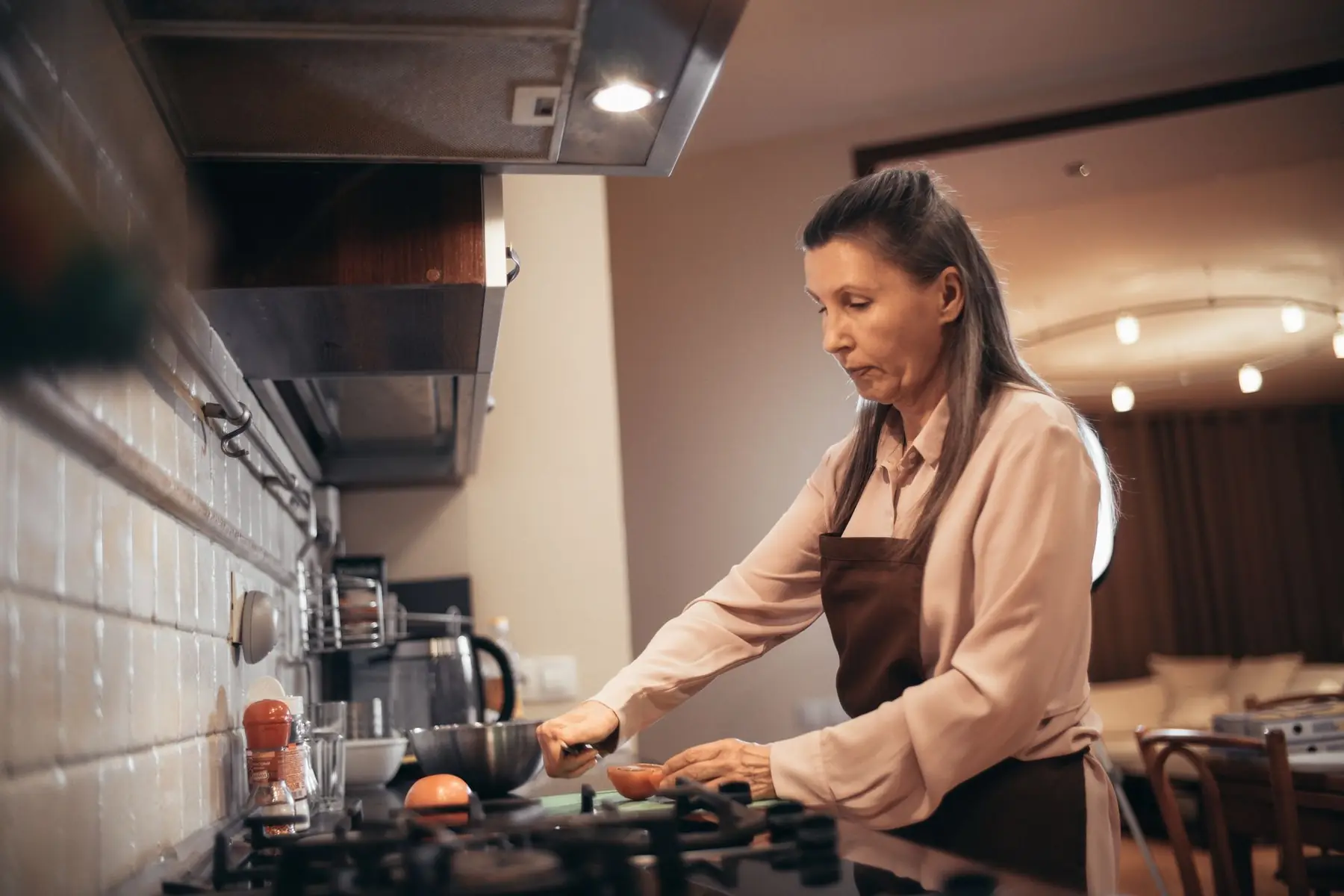Elderly woman prepares food in a warm, cozy kitchen environment