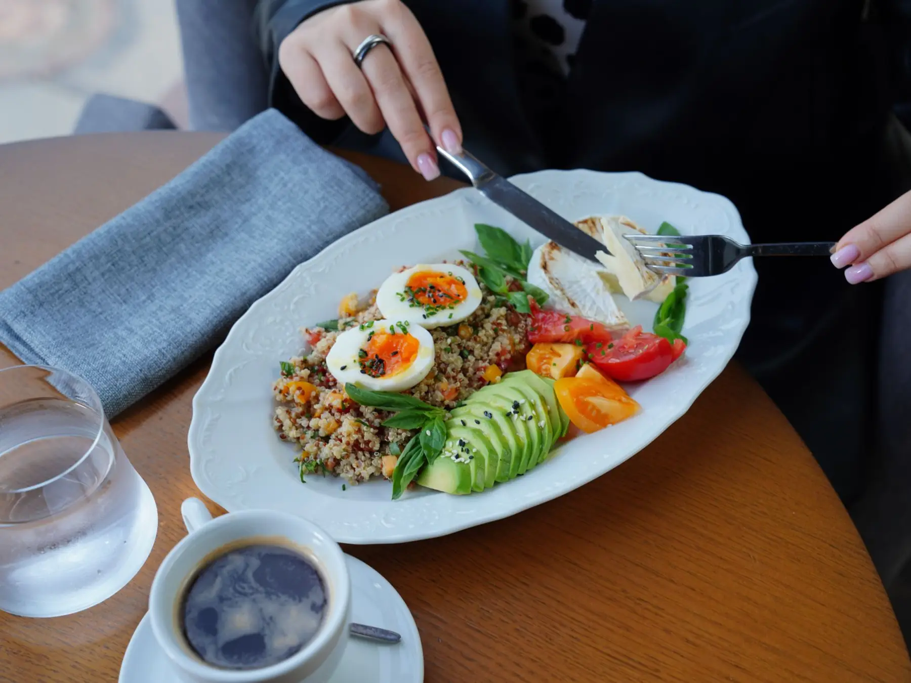 A delicious and healthy breakfast featuring avocado, eggs, and coffee served on a wooden