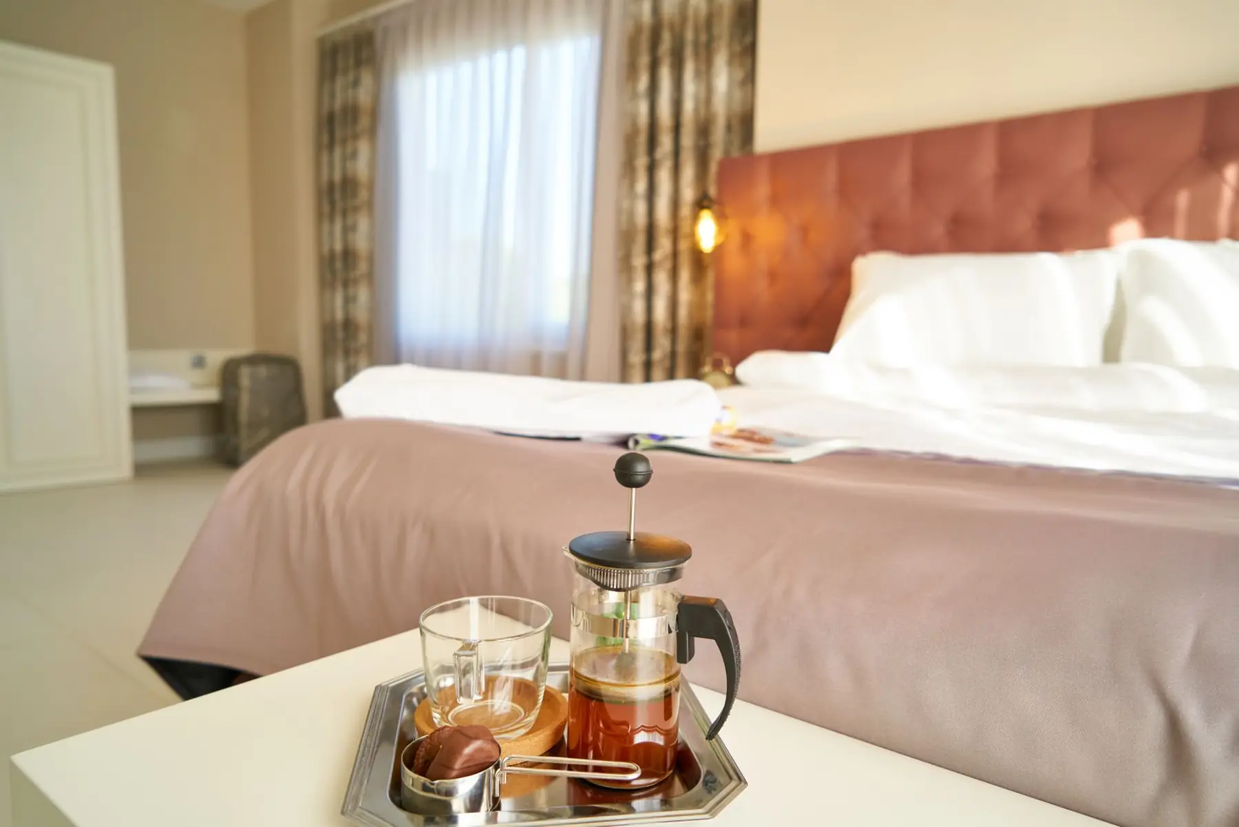 Inviting hotel room with a French press coffee setup on the bedside table, perfect