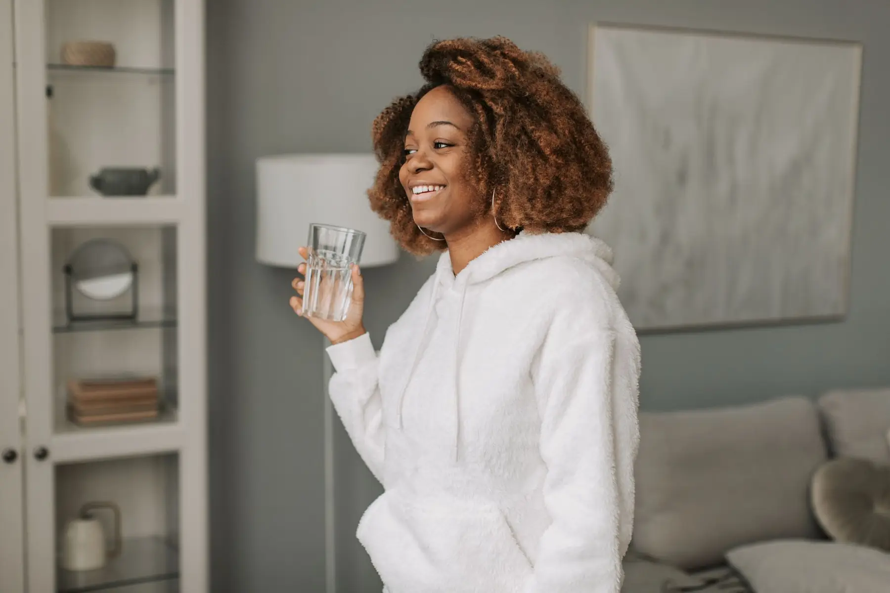 African American woman in a cozy hoodie with a glass of water, starting her