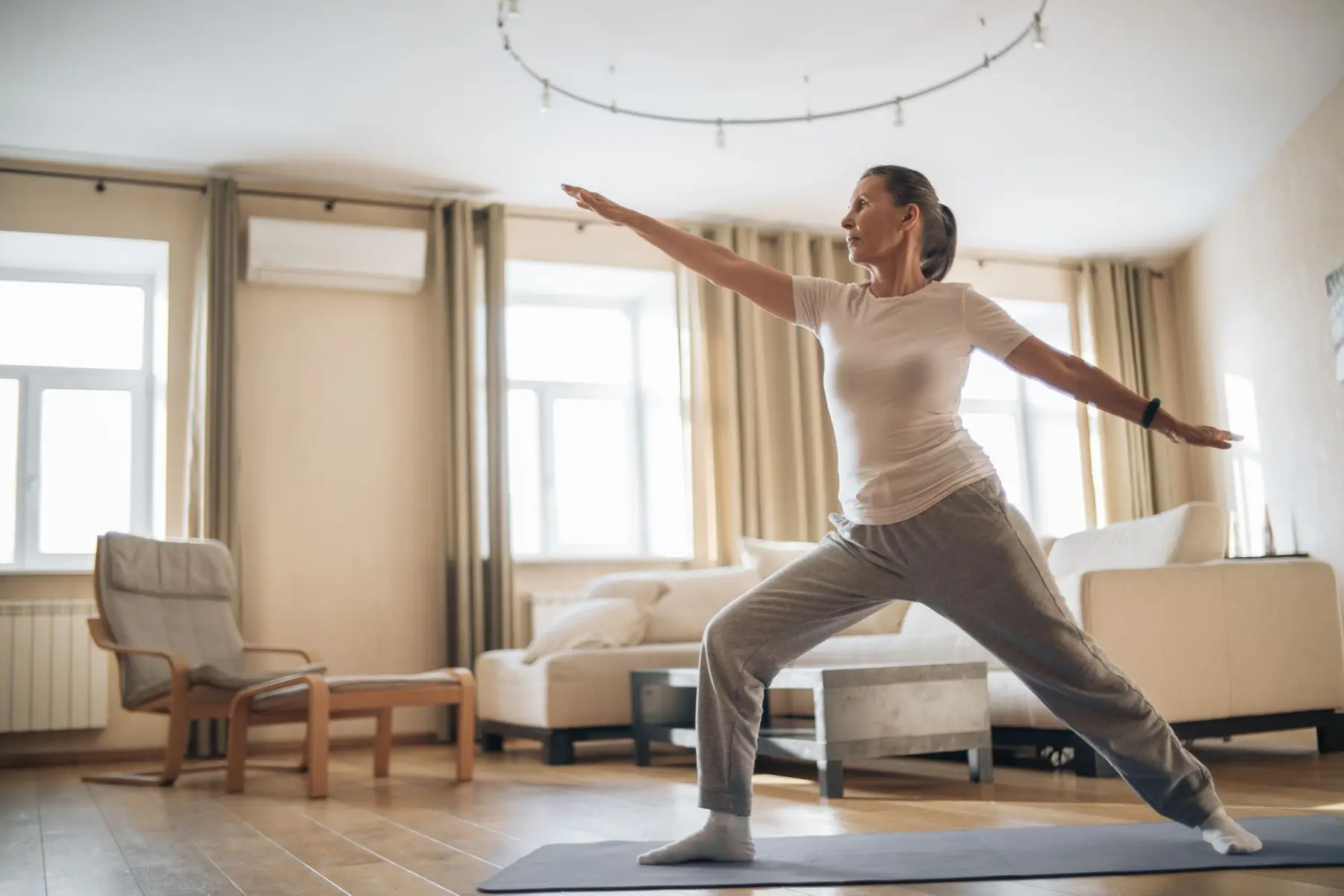 Elderly woman enjoying yoga and stretching exercises at home, promoting wellness and healthy living