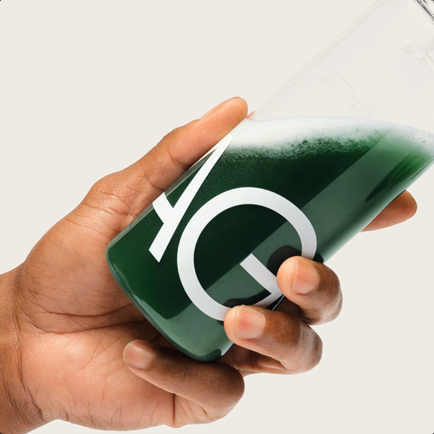 A hand holding a bottle of mixed AG1