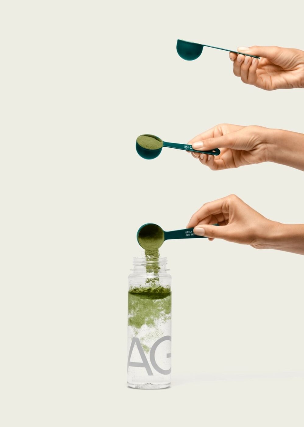 Three scoops of AG1 going into a water bottle