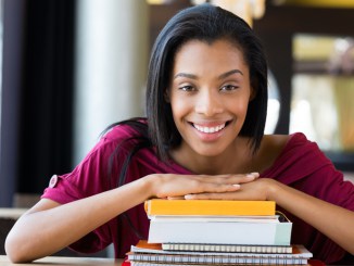 Student girl leans on stack of books
